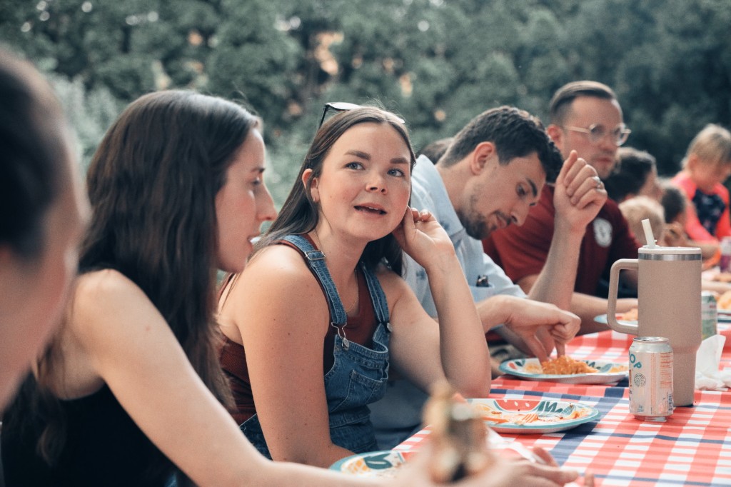 Two women in conversation across a table during a church fellowship meal