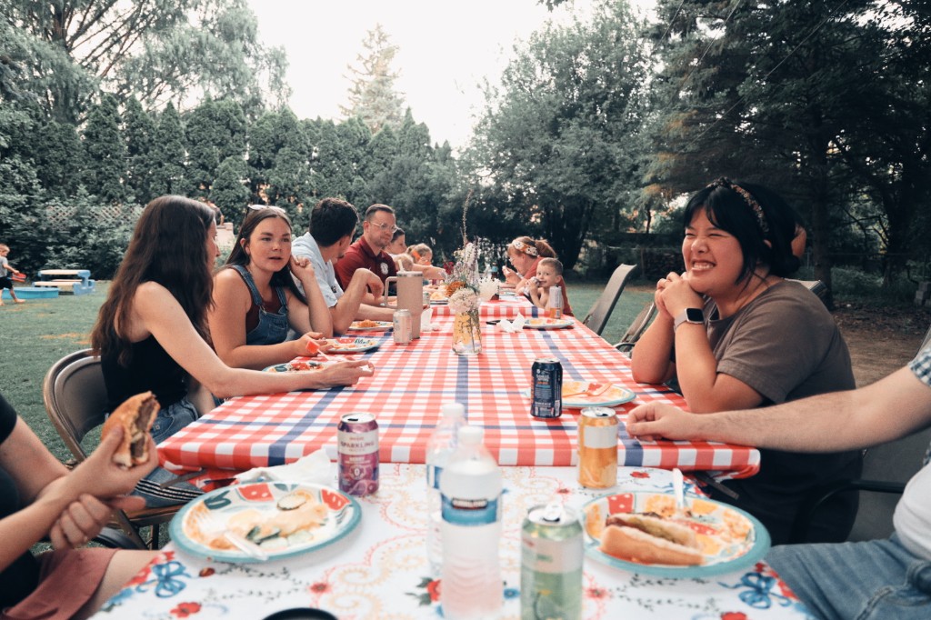 Members of CCLC sharing a summer meal at a long checkered table outdoors