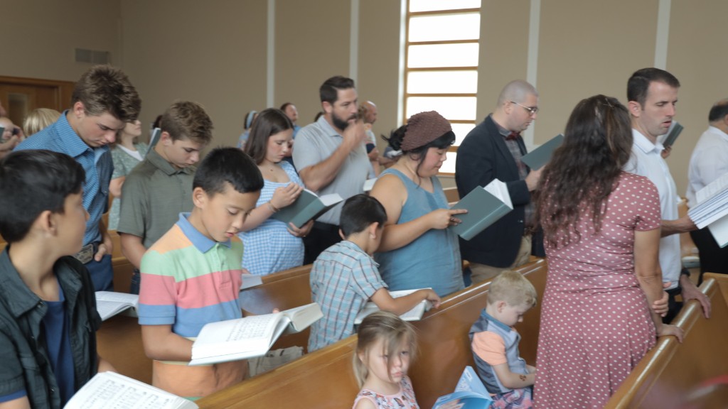 Members of all ages standing in the pews and singing from psalters during a Sunday service at CCLC