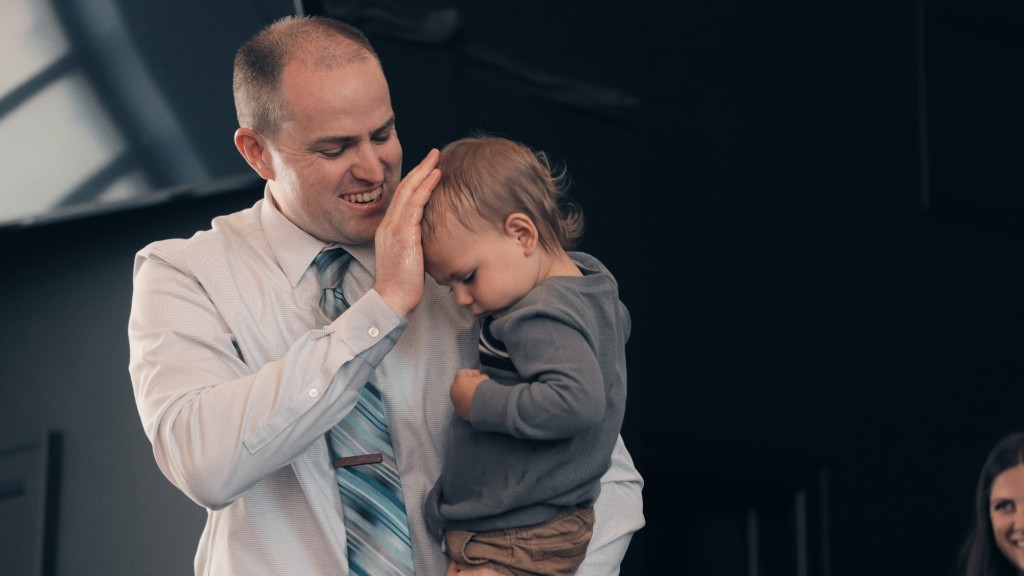 A father smiling as he lays his hand on his young child's head in blessing during worship